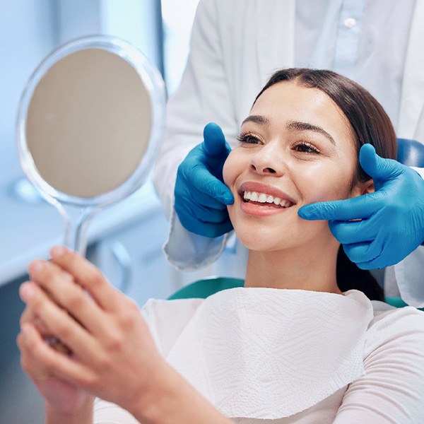 Woman smiling at reflection in handheld mirror