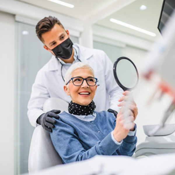 A senior woman admiring her smile in a dental office