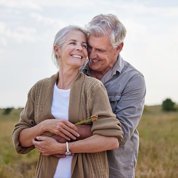 Senior man and woman hugging in a field