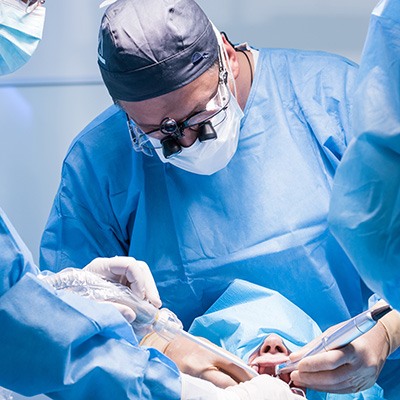 Dentists in blue scrubs performing oral surgery
