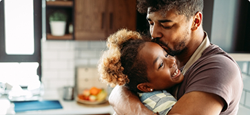 Father kissing his daughter on the top of her head