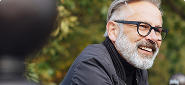 Man with gray hair and glasses smiling outdoors